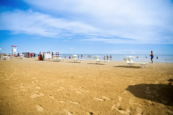 Spiaggia prospiciente il mare con lettini e persone a passeggio