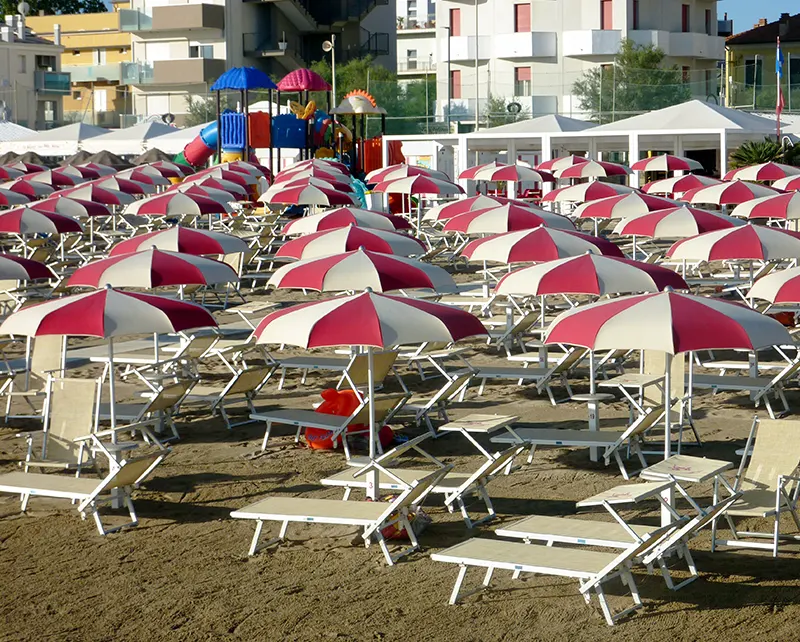 File di ombrelloni a spicchi bianchi e rossi sulla spiaggia