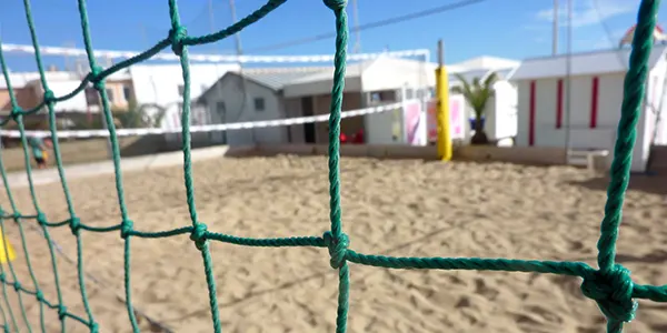 Campo da beach volley in sabbia visto attraverso la rete