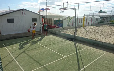 Due bambini che giocano a basket su un campo da pallacanestro a fondo verde